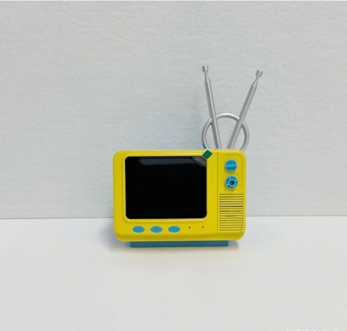 Esse mini console retrô é tão emocionante!  O corpo amarelo e azul é uma réplica de uma TV antiga, e vem com jogos clássicos como Contra.  O controle sem fio tem uma sensação que replica a do antigo console Pong.  Pode ser tocada na mão ou como um item decorativo.  Você pode carregar no bolso.  Assim que liga, ele te transporta instantaneamente de volta ao fliperama da infância.  Jogando online ou sozinho, tudo é divertido.