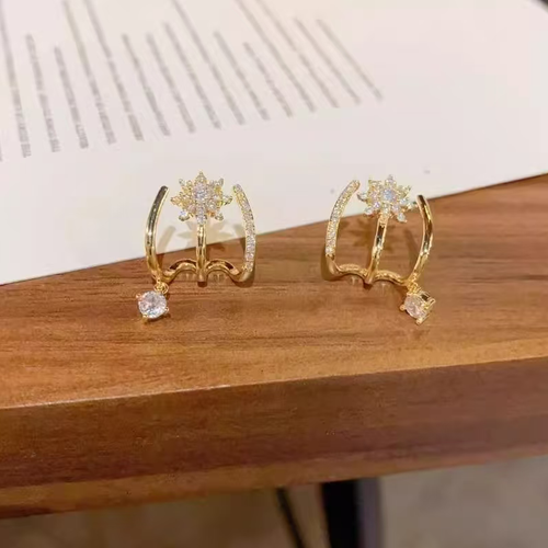 Estes brincos em forma de estrela octogonal apresentam um design curvo integrado que se adapta perfeitamente ao ouvido. Os brincos são adornados com pequenas pedras de zircônio e um delicado pingente, proporcionando uma aparência suave e brilhante. O design é único e moderno, com um estilo japonês-coreano. São adequados tanto para uso diário quanto para encontros sociais.  evita-se o impacto e a exposição a produtos químicos, garantindo a preservação duradoura da qualidade do joalharia.