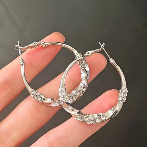 Estes brincos em forma de anel com zircônia e diamante torcido apresentam um design redondo clássico, com zircões delicadamente dispostos em um padrão. A superfície é lisa e brilhante. O fecho de encaixe garante uma fixação segura. A superfície metálica é polida e lisa. É versátil e adequado para diversos tipos de looks, ideal tanto para uso profissional como casual. Com a manutenção adequada, pode conservar sua textura por muito tempo.