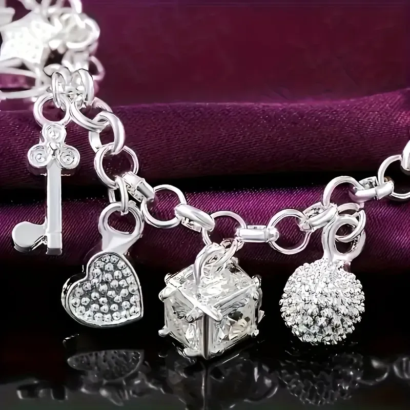 An elegant 925 sterling silver bracelet featuring a heart-shaped key pendant and adorned with 13 exquisite mini-charms, exuding a charming Bohemian style. Boasting a radiant silver luster and meticulous craftsmanship, this fashionable accessory makes an ideal gift for a wife or girlfriend—perfect for birthdays or any special occasion—and serves as a striking, personalized statement piece. (Box not included.)