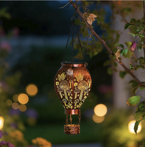 A hot air balloon-shaped solar ironwork pendant light. With a retro distressed material that is rust-proof and waterproof. The design features a hollow mushroom and butterfly pattern. It casts beautiful light at night. Solar-powered for self-charging. Controlled by light, it automatically turns on and off without the need for wiring. Suitable for hanging in the garden or balcony, it can easily create a cozy and pleasant outdoor atmosphere.