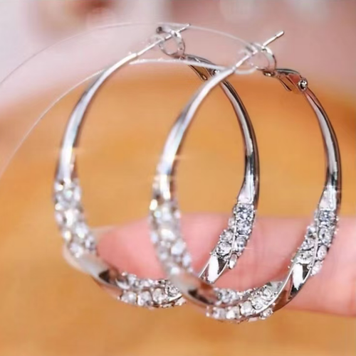 This twisted diamond-set zirconia hoop earrings feature a classic round design, with zircons delicately arranged in a pattern. The surface is smooth and shiny. The snap fastening ensures a secure fit. The metal surface is polished and smooth. It is versatile and suitable for various outfits, suitable for both work and casual wear. With proper maintenance, it can maintain its texture for a long time.