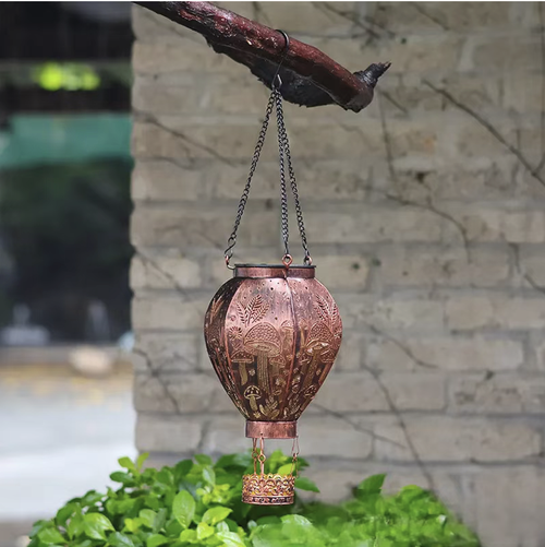 A hot air balloon-shaped solar ironwork pendant light. With a retro distressed material that is rust-proof and waterproof. The design features a hollow mushroom and butterfly pattern. It casts beautiful light at night. Solar-powered for self-charging. Controlled by light, it automatically turns on and off without the need for wiring. Suitable for hanging in the garden or balcony, it can easily create a cozy and pleasant outdoor atmosphere.