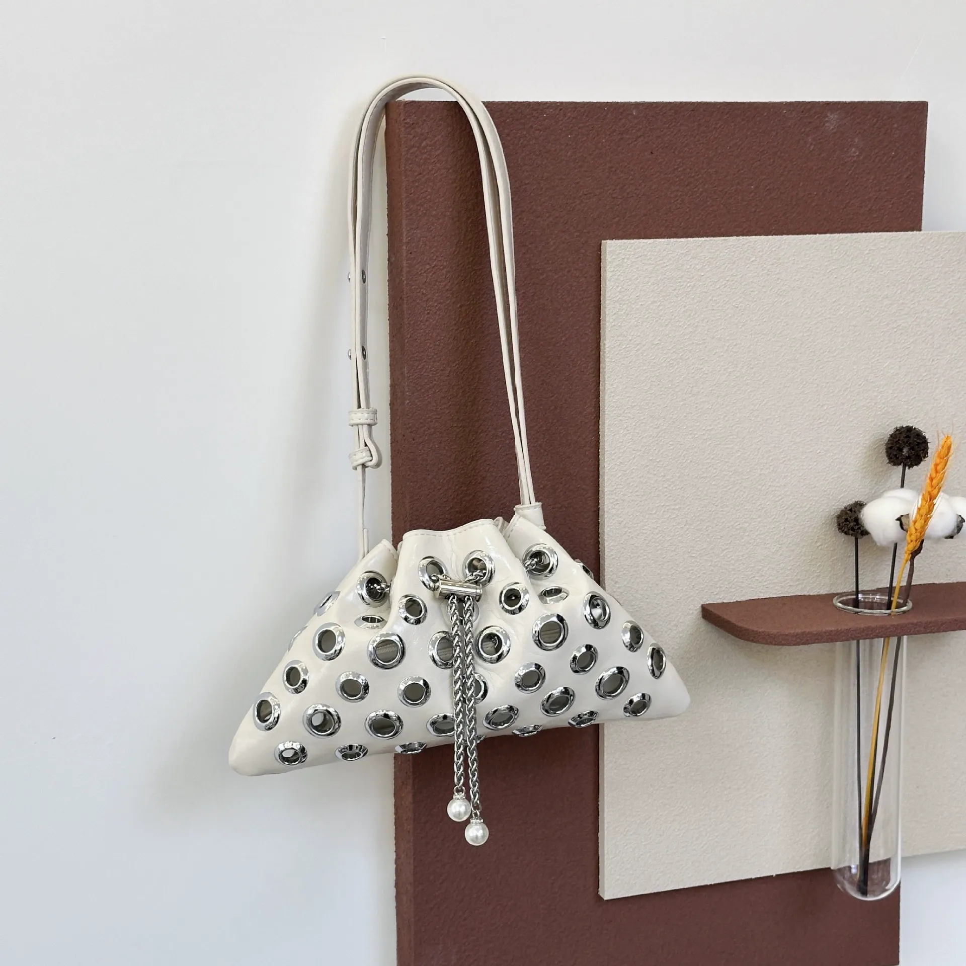 Stylish single-shoulder crossbody bag with openwork drawstring bucket bag, handle with underarm rivets, versatile small bag for women.