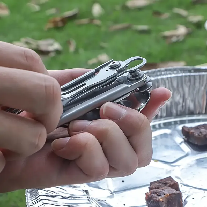 A Versatile Folding Outdoor Tableware Set With 5 In 1, Including Knife, Fork, Spoon, Bottle Opener, Made Of Stainless Steel, Easy To Clean, And Comes With A Storage Bag, Perfect For Camping.