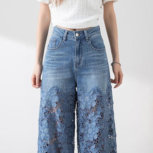 Women's high-waisted blue jeans with wide legs, distressed detailing and lace inserts.