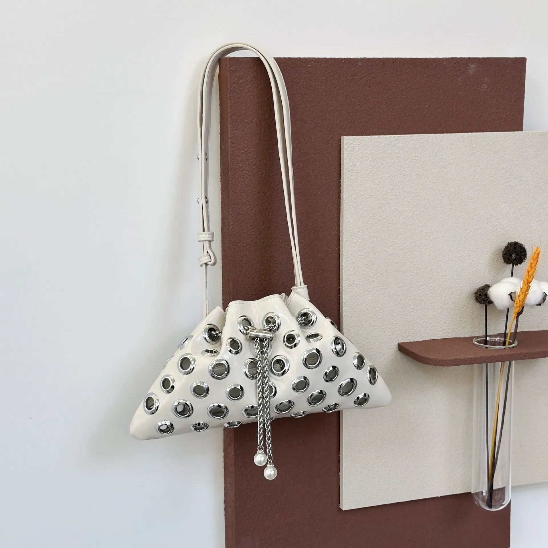 Stylish single-shoulder crossbody bag with openwork drawstring bucket bag, handle with underarm rivets, versatile small bag for women.